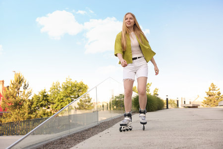 Happy woman roller skating on city street. Space for text