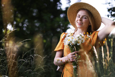 Beautiful woman with bouquet of wildflowers in meadow
