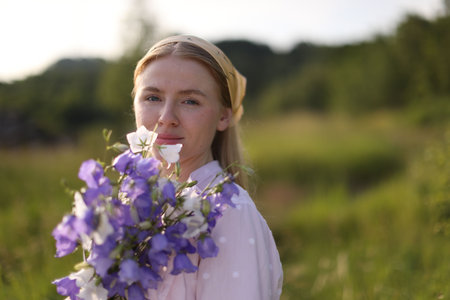 Beautiful woman with bouquet of wildflowers in meadow on sunny day. Space for textの写真素材