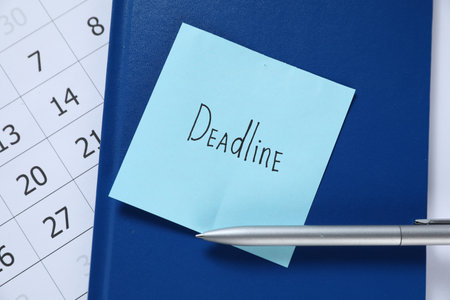Sticky note with word Deadline, notebook, pen and calendar on table, top viewの写真素材