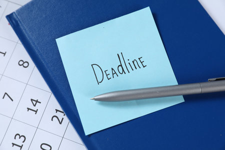 Sticky note with word Deadline, notebook, pen and calendar on table, top viewの写真素材