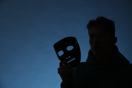 Anonymity. Silhouette of man with mask on blue backgroundの写真素材