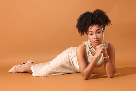 Fashionable portrait of beautiful Brazilian woman in stylish outfit on light brown backgroundの写真素材