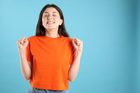 Portrait of surprised woman on light blue background, space for textの写真素材