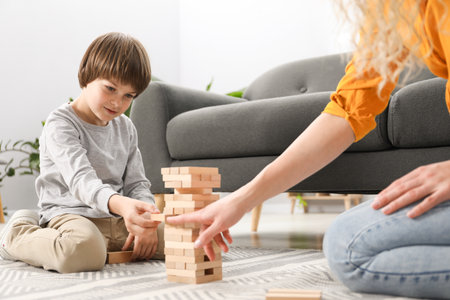Mother and her son playing with wooden constructor blocks on floor at home, closeupの写真素材
