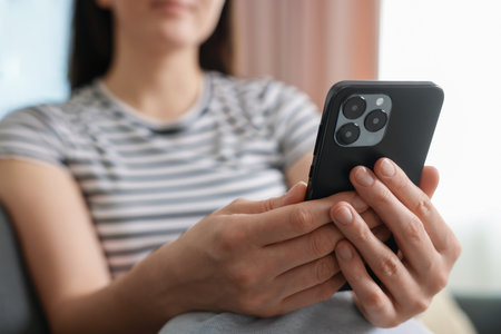 Woman using modern smartphone at home, closeupの写真素材