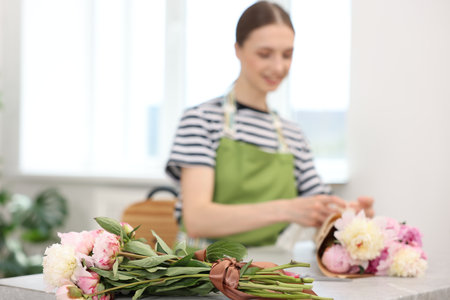 Florist making bouquet of peonies at table in flower shop, selective focusの写真素材