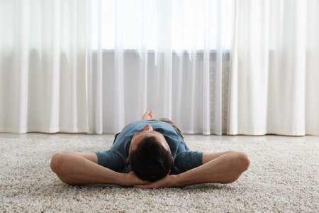 Harmony. Man lying on rug at homeの写真素材