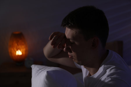 Frustrated man with pillow suffering from insomnia indoors, space for textの写真素材