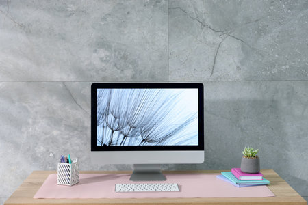 Stylish workplace with computer and pink mousepad on wooden table indoors