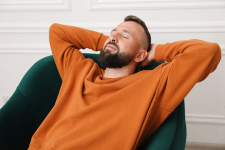 Harmony. Man relaxing in comfortable armchair at homeの写真素材