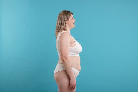 Weight loss. Plus size woman in underwear on light blue backgroundの写真素材