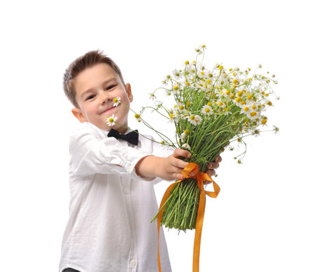 Cute little boy giving bouquet of beautiful chamomile flowers on white backgroundの写真素材