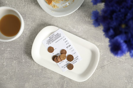 Tips, receipt, dirty plate and cup on grey table, flat layの写真素材