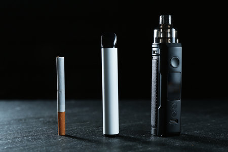 Electronic smoking devices and cigarettes on black tableの写真素材