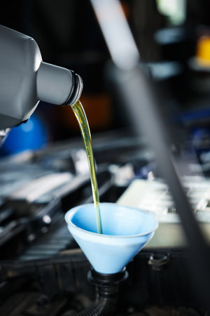 Pouring motor oil from bottle into car engine, closeupの写真素材