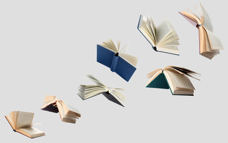 Hardcover books flying like birds against grey backgroundの写真素材
