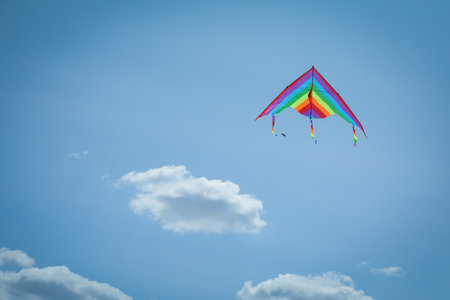 Colorful kite flying in blue sky, low angle view. Space for textの写真素材
