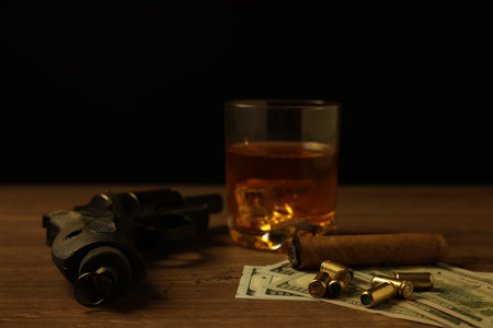 Mafia and criminal world. Gun, bullets, money, cigar and whiskey on wooden table, closeup