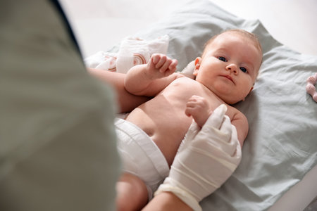 Pediatrician examining baby at table in clinic, closeup