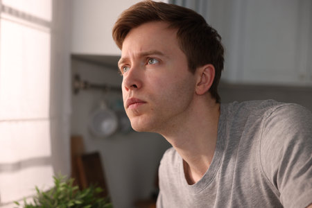 Young man suffering from paranoia in kitchen