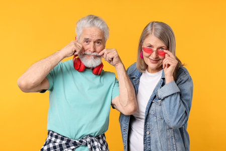 Senior couple in stylish outfits on orange backgroundの写真素材