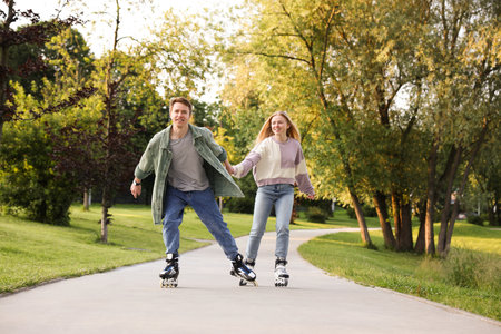 Happy couple roller skating together in parkの写真素材