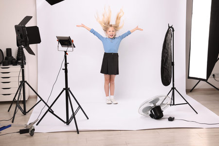 Little girl on white background in photo studio with professional equipment