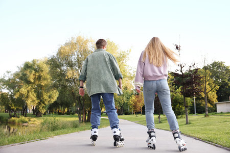 Couple roller skating together in park on summer day