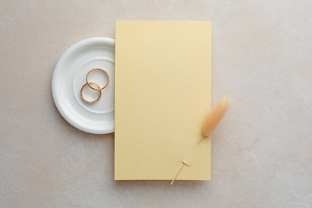 Wedding invitation card with spike and golden rings on color textured table, top viewの写真素材