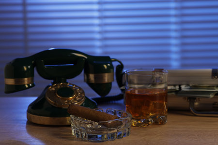 Mafia and criminal world. Money, whiskey, cigar and telephone on wooden table indoorsの写真素材