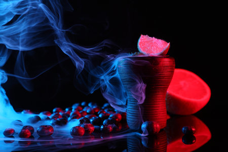 Hookah bowl with smoke and fruits on black table in neon lights, closeup