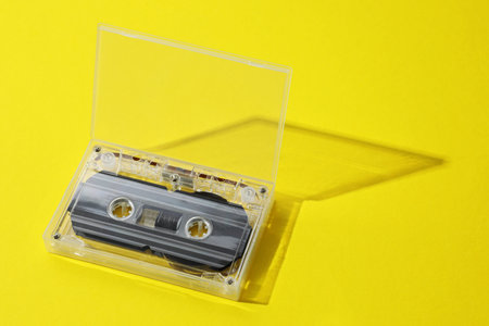 One audio cassette in open box on yellow backgroundの写真素材