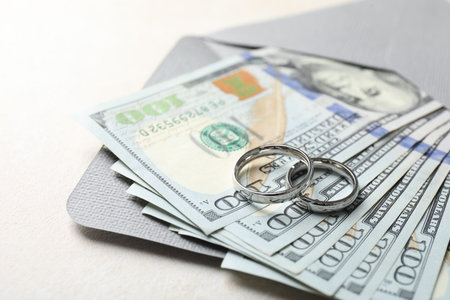 Two silver wedding rings, dollar banknotes and envelope on white table, closeupの写真素材