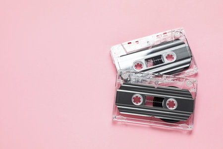 Audio cassettes with magnetic tapes on pink background, flat lay. Space for text