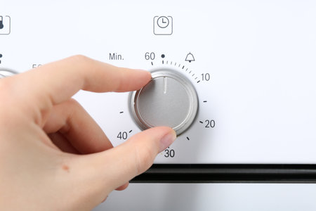 Maximum concept. Woman turning on oven, closeupの写真素材
