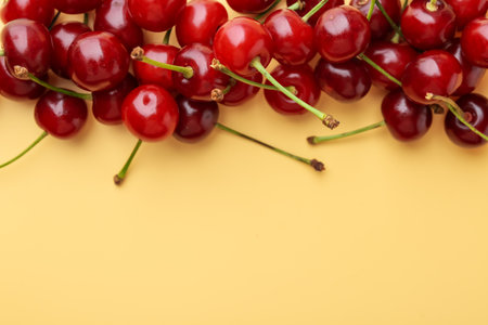 Fresh ripe cherries on beige background, flat lay. Space for textの写真素材
