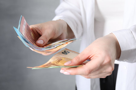 Woman counting euro banknotes on gray background, closeupの写真素材