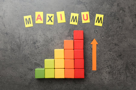 Word Maximum, arrow and colorful cubes on gray table, flat layの写真素材