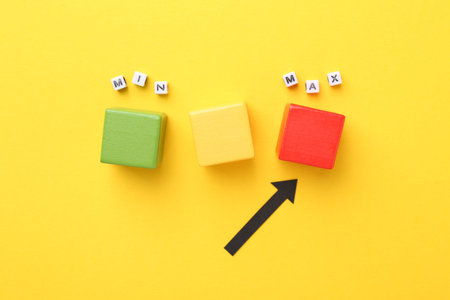 Words Max and Min, cubes and arrow pointing at red one on yellow background, flat lay
