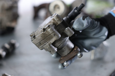 Auto part. Professional mechanic with power steering pump indoors, closeup