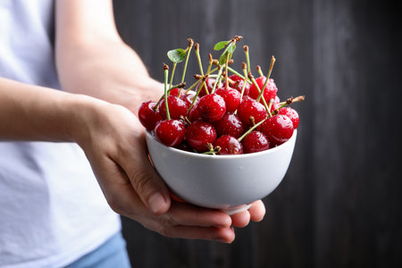 Woman with wet ripe cherries on black background, closeupの写真素材