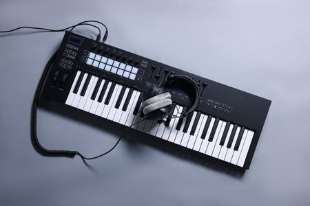 MIDI keyboard with headphones on gray background, top view