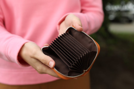 Woman with open empty wallet outdoors, closeup