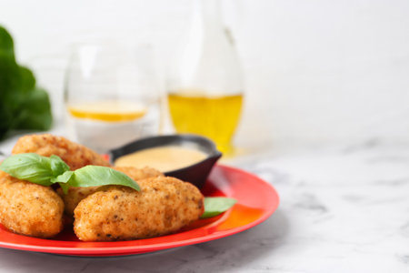 Tasty fried croquettes, basil and sauce served on white marble table, closeup. Space for textの写真素材