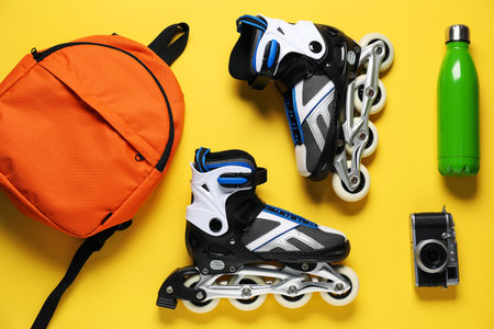 Flat lay composition with roller skates on yellow background