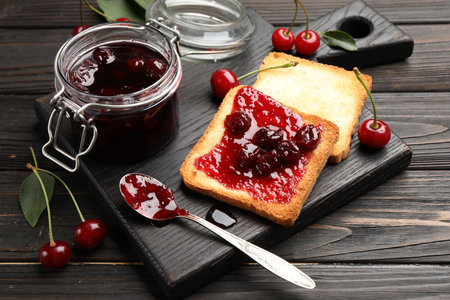 Toasts with tasty cherry jam and fresh fruits on black wooden table, closeupの写真素材