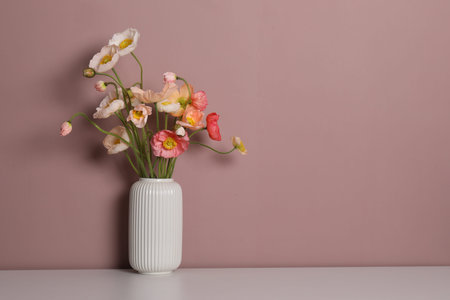 Beautiful poppy flowers in vase on white table against pink background. Space for textの写真素材