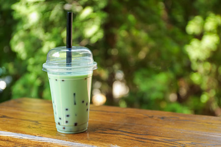Tasty milk bubble tea in plastic cup on wooden table. Space for textの写真素材