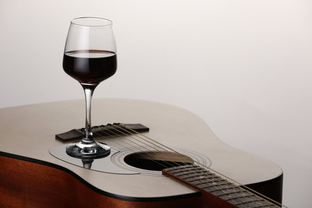 Acoustic guitar and red wine on white background, closeup. Space for textの写真素材